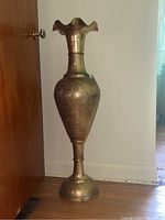 Full view of the tall etched brass vase showing its body, etched details, and flared top rim.