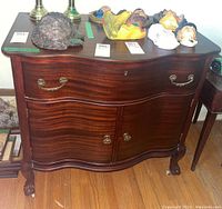 Front view of vintage wooden cabinet on wheels with two drawers and two cupboard doors, showing brass hardware and rich wood finish.