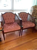 Pair of cane barrel back chairs with tufted crushed corduroy upholstery in dusty rose color. Wooden frames with cane side panels and turned legs.