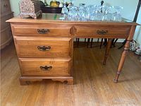 Full front angle view of the Roxton maple desk showing drawer fronts and one leg.