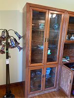 Front view of wood display wall cabinet with upper and lower glass doors, showing shelves and drawers inside.