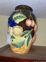Front and side view of the 14 inch ceramic vase with colorful fruit including grapes, pears, cherries, and leaves in raised painted detail.