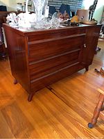 Full view of sideboard showing three drawers on left and closed cabinet on right with objects on top.
