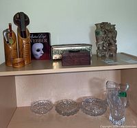 Shelf with carved wooden pencil holder set, Andrew Lloyd Webber discs, metallic and wooden boxes and beige marble carved statue