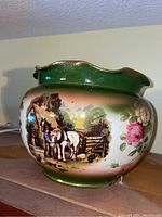 Front-left view showing farm scene with horses and rider and floral accents on green background