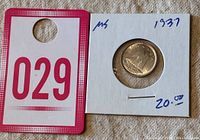 Photo showing the coin in a protective holder with a price tag and lot number for identification.