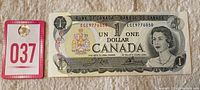 Photo showing the front of the 1973 Canada one dollar banknote alongside a numbered tag.