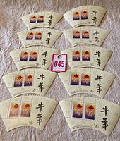 Overview of 10 fan-shaped souvenir sheets each containing two Year of the Ox stamps, arranged on a textured surface with a lot tag.