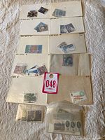 Set of small envelopes and plastic sleeves containing various mint British stamps organized by denomination and type.