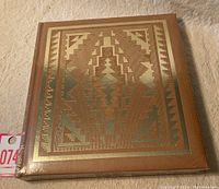 Hardcover book with brown luxe cover embossed with gold Native American geometric pattern, sealed in shrink wrap.