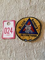 Patch alongside lot number card on fabric background showing size and detail of embroidery.