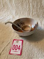 Full view of Noritake sauce bowl with curved spoon resting inside the bowl, showing shape and size