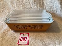 Photo of the rectangular Pyrex Old Orchard dish in orange with fruit pattern on side and clear ribbed lid.