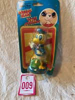 Full frontal photo of the Donald Duck bobblehead figure inside original blue card backing and clear plastic blister packaging. The blister shows some creases and the card backing has discoloration and wear.