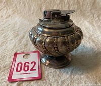 Side angle of vintage Ronson table lighter showing silver-tone ornate bulbous body and chrome lighter top