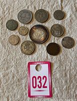 Photo showing all 11 coins in the lot on a white textured background, displaying various sizes and designs.