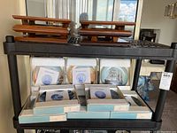 Photo showing eight boxed limited edition collector plates by Alan D'Estrehan arranged on shelves with wood display stands on top.