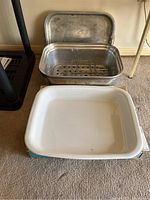 Photo of metal roasting pan with lid and interior racks, showing wear