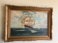 Full view of oil painting of a sailing ship at sea in gilded wood frame