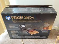 Back view of the HP DeskJet 3050A box showing printer model and features including wireless printing and scanning capabilities.