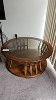 Top view of round coffee table showing glass top and wood frame with curved supports