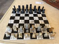 Full set of onyx and marble chess pieces arranged on matching 12x12 onyx and marble board, showing dark black and light stones with natural veining and the entire set.