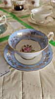 Porcelain teacup and saucer showing blue and gold decorative edges with floral pattern in center.