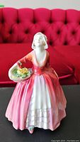 Full view of Royal Doulton Janet figurine in pink and white dress holding flower basket.