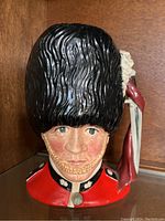 Front view of Royal Doulton Guardsman Toby jug showing detailed face, bearskin hat, and red jacket collar.