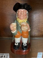 Front view of the Royal Doulton Happy John Toby mug showing the character holding two mugs, dressed in period clothing including a black tricorne hat and yellow neckerchief.