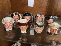 Photo of all eight Royal Doulton Toby character mugs and jugs arranged together showing front faces and handles