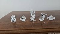 Photo showing all five Swarovski crystal animal figurines arranged in a line on a wooden surface, displaying the fox, duck, squirrel, koala, and puffer fish figurines clearly with faceted crystal details.