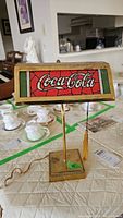 Frontal view of the Coca-Cola glass shade and brass base showing lamp details and tassel.