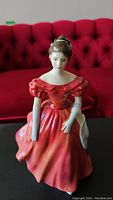 Front view of the Royal Doulton Winsome figurine showing detailed face and the red dress against a red background.