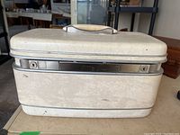Front view of a vintage off-white Samsonite hard shell vanity case with visible marks on outer surface.
