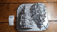 Aluminum vintage Christmas tree shaped cake pan with detailed tree design and star topper. Pan shows natural wear but retains shape and detail.