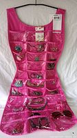 Full view of pink dress-shaped hanging jewelry organizer filled with various costume jewelry items including bracelets, necklaces, brooches, and sunglasses.