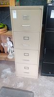 Front view of beige metal filing cabinet with four drawers showing wear and scratches.
