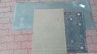 Three mats stacked: tan cushion mat on top, black floral entrance mat underneath, and large dark grey mat at bottom