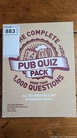 Photo showing the front of the unopened box for The Complete Pub Quiz Pack featuring branding and claim of more than 1,000 questions.