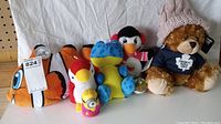 Photo showing assortment of six plush toys arranged side by side on fabric background