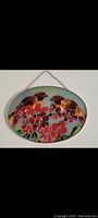 Photo showing one oval stained glass wall hanging featuring two birds and red flowers with a metal chain hanging from the top.