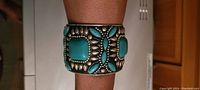 Wide view of the turquoise and silver tone cuff bracelet on arm, showing the overall design and size.
