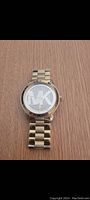Clear photo of Michael Kors watch showing gold tone bracelet and crystal embellished MK logo dial