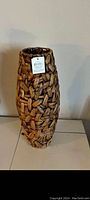 Front angle view of new medium-sized woven wicker vase with tag attached