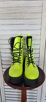 Front view of neon yellow boots showing black laces and black chunky sole.