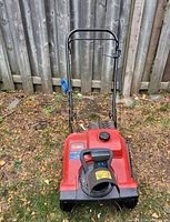 Front left angled view showing red body, black snow discharge chute, and blue control lever on handle.