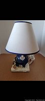 Front view of the Toronto Maple Leafs table lamp with cream-colored shade on a wooden surface.