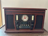 Front view of the radio/CD recorder showing wooden casing, analog AM/FM dial, speaker grills
