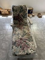 Full view of the white plastic lawn chair with floral cushion, showing seat and extended backrest.